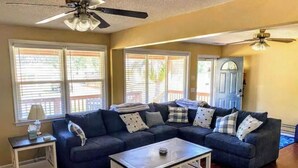 A living room with a sectional sofa, a coffee table, a side table, and a ceiling fan. - Cozy ranch, minutes from both historic downtown Savannah and Tybee Beaches. (Savannah)