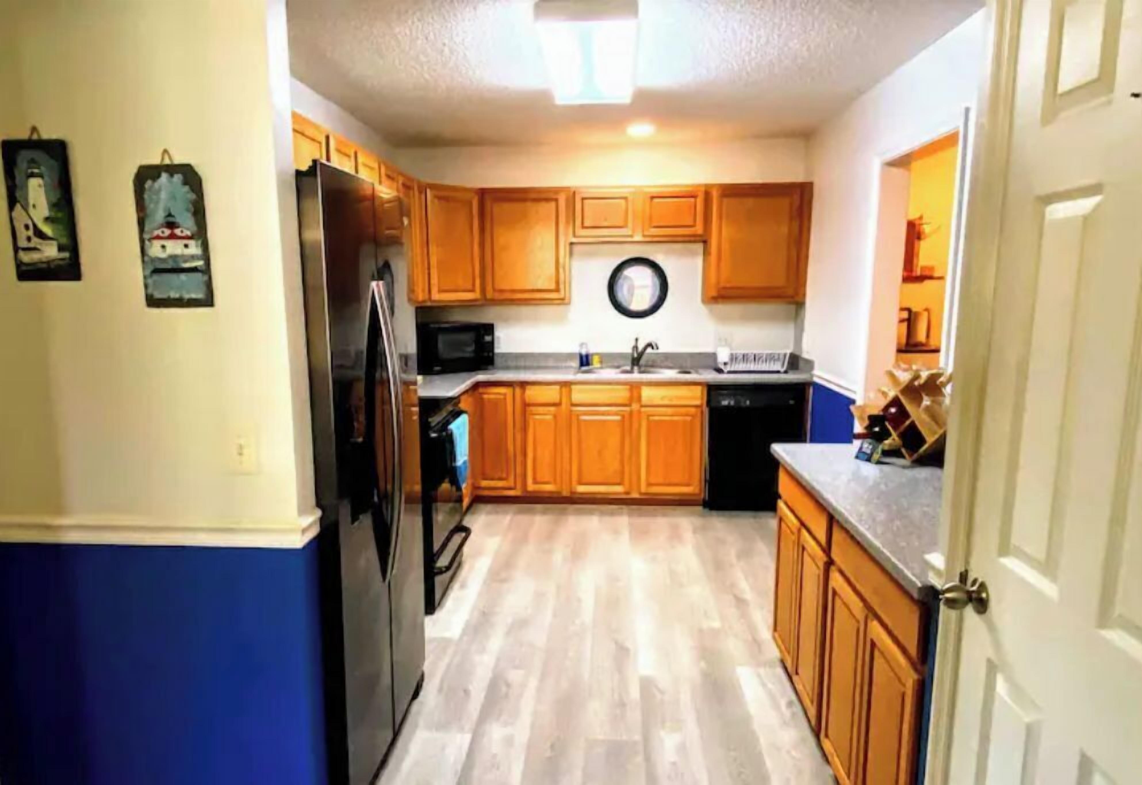 A kitchen with wooden cabinets, a refrigerator, a microwave, and a dishwasher.