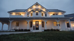 A two-story house with a front porch, multiple windows, and a well-lit entrance. - Ann Riley Farmhouse Yuba Vineyards (Williamsburg)