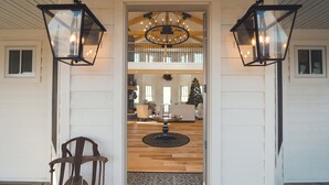A foyer with a wooden floor, a patterned rug, a chandelier, and two wall-mounted lanterns. - Ann Riley Farmhouse Yuba Vineyards (Williamsburg)