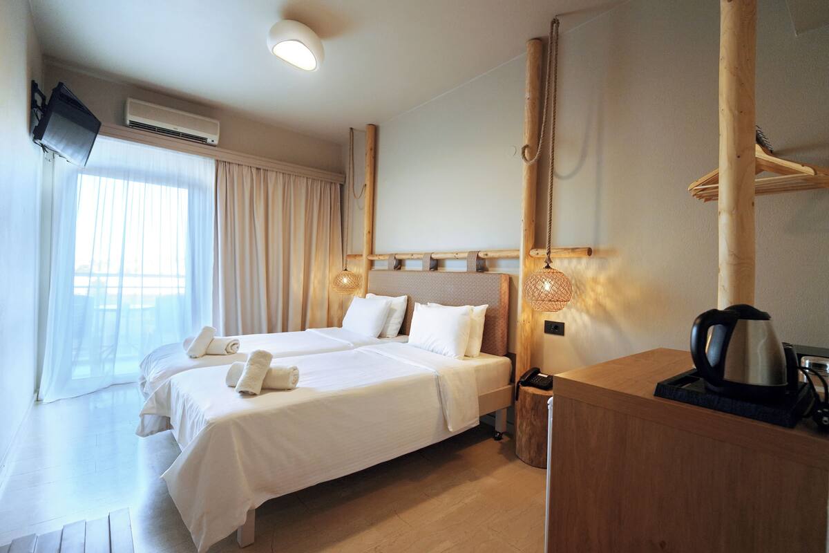 A hotel room with two beds, a wooden desk, a coffee maker, and a TV mounted on the wall.