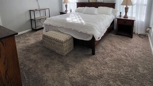 A bedroom with a large bed, two bedside tables, a TV mounted on the wall, and a carpeted floor. - Hillside Relaxation in Endless Mountains. Minutes from Tioga Downs. Sleeps 8 (Rome)