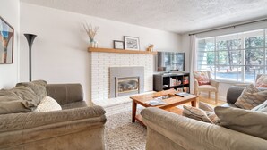 A living room with a fireplace, sofas, a coffee table, and a bookshelf. - Westside Bend: Walk to Eateries & Downtown! (Bend)