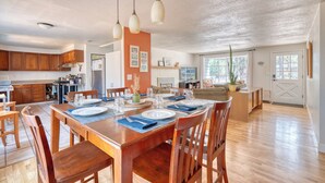 A spacious kitchen with wooden cabinets, a dining area with a wooden table set for four, and a living area with a sofa and a coffee table. - Westside Bend: Walk to Eateries & Downtown! (Bend)