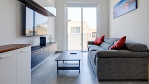 A modern living room with a sofa, a coffee table, and a TV mounted on the wall. - Contemporary 3BR Retreat in Prime Sliema (Sliema)