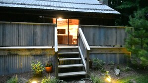 Eine rustikale Holzhütte mit einer Holztreppe, die zu einem Eingang mit Glastür führt.