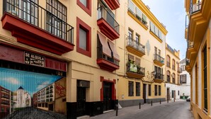 Una stretta via fiancheggiata da edifici colorati, con balconi e un negozio con insegne ben visibili.