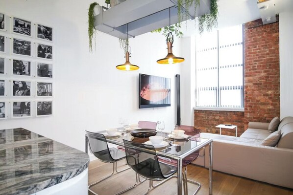 A modern living space with a dining area, a sofa, and a brick wall.