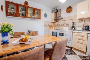 Una cocina moderna con una mesa de comedor de madera, horno empotrado y cafetera.