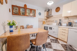 A modern kitchen with a dining table, chairs, cabinets, and a stove. - Private Villa with Saltwater Pool Near Crikvenica (Grižane-Belgrad)