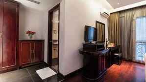 A hotel lobby with a wooden cabinet, a television on a stand, a small table with a bottle and fruit, and a door leading to another room. - Hanoi Memory Central Hotel & Spa (Hanoi)