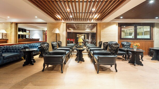 A spacious lobby with a central coffee table surrounded by leather chairs, a blue sofa, and a wooden ceiling with recessed lighting. - Hanoi Memory Central Hotel & Spa (Hanoi)