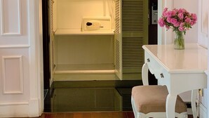 A room with a white desk, a chair, a small table with a vase of flowers, and a closet with a hanging rack. - Hanoi Memory Central Hotel & Spa (Hanoi)