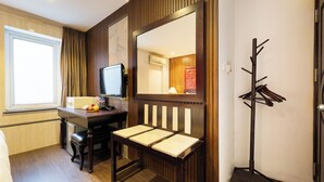 A hotel room with a wooden desk, a chair, a television, a coat rack, and a window with curtains. - Hanoi Memory Central Hotel & Spa (Hanoi)