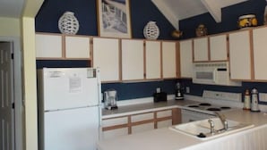 A compact kitchen with white cabinets, a refrigerator, a microwave, a stove, and a sink.