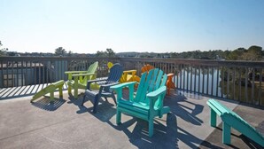 Una terraza con sillas Adirondack de colores y un banco con vista al agua.