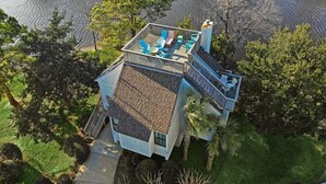 Een huis met twee verdiepingen en een balkon met uitzicht op een meer, omringd door bomen.