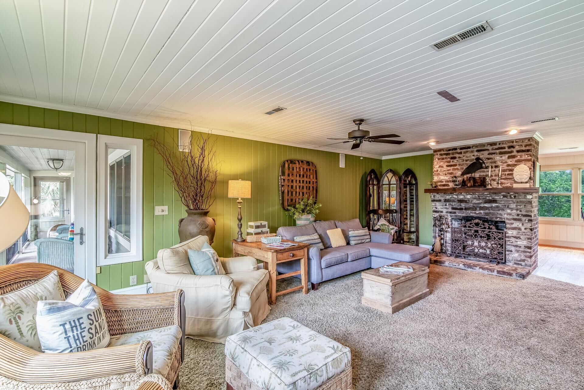 A cozy living room with a green wall, a fireplace, and a ceiling fan.