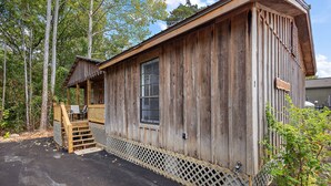 Une cabane en bois rustique avec un porche et une petite terrasse.