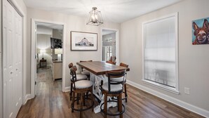 Un coin repas avec une table et des chaises en bois, un lustre et un tableau représentant un cheval accroché au mur.