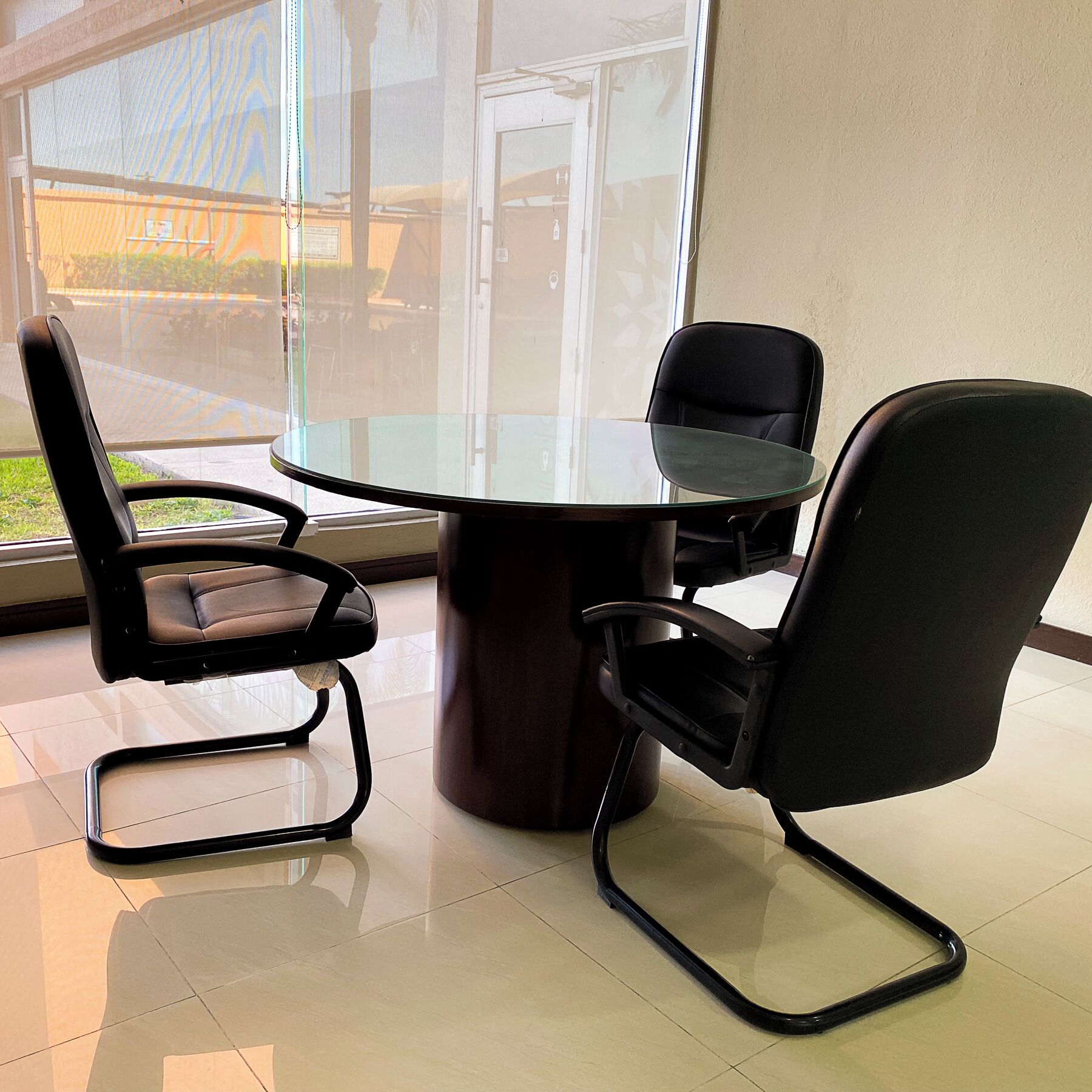 Una sala de reuniones moderna con una mesa de vidrio y sillas negras.