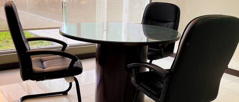 Una sala de reuniones moderna con una mesa de vidrio y sillas negras.