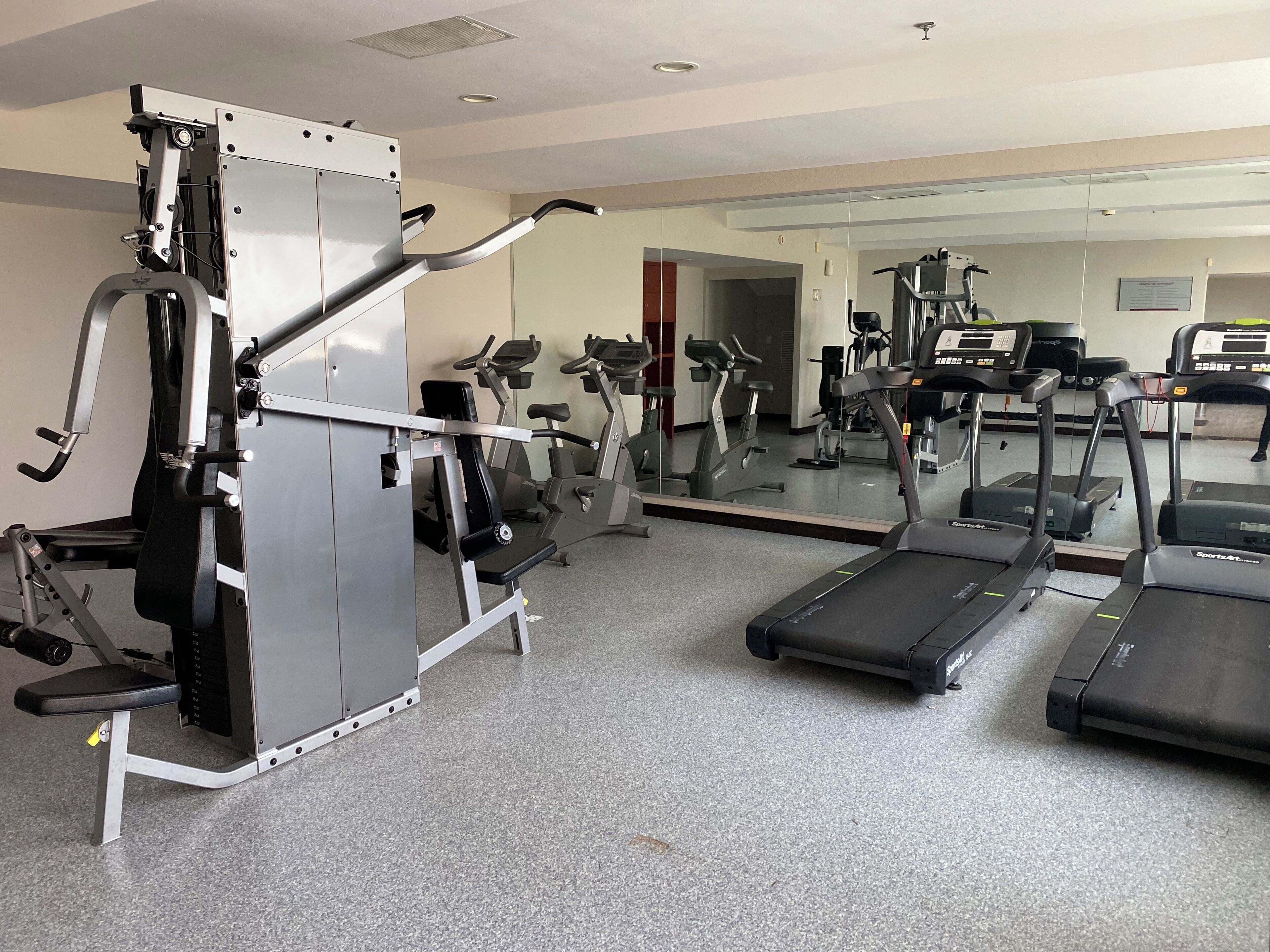 A gym with various exercise equipment including treadmills, elliptical machines, and weight machines.