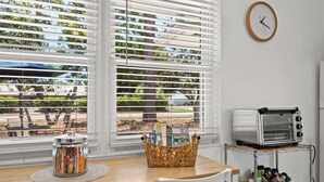 A kitchen with a wooden table, white chairs, a toaster, and a basket of magazines. - Siesta Keys Neighbor 5min to Beach - Entire Suite Apartment (Sarasota)