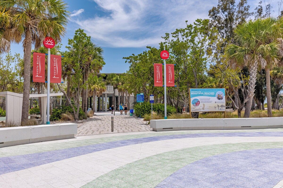 A pathway leading to a beach area with palm trees and a clear sky.