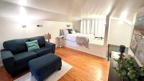 Un dormitorio moderno con cama, mesita de noche, lámpara y un amplio ventanal con cortinas.