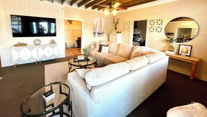 Una sala de estar con un sofá, una mesa de centro, un televisor y un ventilador de techo.