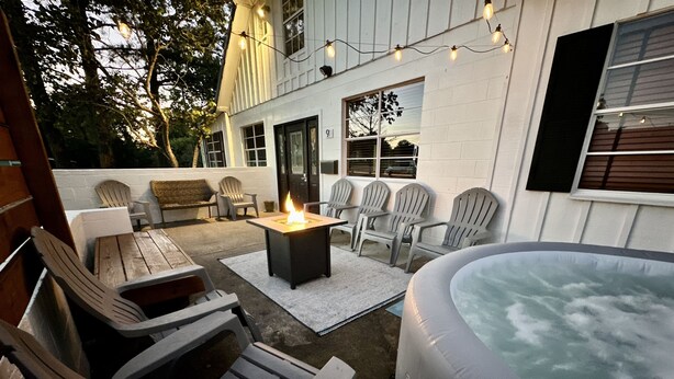 Un patio al aire libre con sillas Adirondack, un pozo de fuego y un jacuzzi.