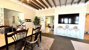 Un comedor con una mesa y sillas de madera, un candelabro y un televisor montado en la pared.