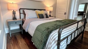 A bedroom with a bed, two bedside tables, a ceiling fan, a wall-mounted artwork, and a door leading to another room. - Spacious 3 Bedroom Sleeps 5 - Walk to Botanical Garden - Long Term Pet Friendly (St. Louis)