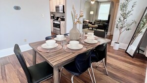 A dining area with a wooden table set for four, surrounded by black chairs. A kitchen is visible in the background. - Spacious 3 Bedroom Sleeps 5 - Walk to Botanical Garden - Long Term Pet Friendly (St. Louis)
