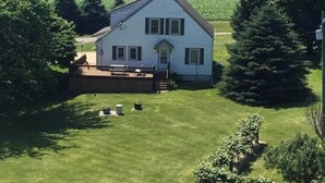 A two-story house with a front porch, surrounded by a well-maintained lawn and trees.