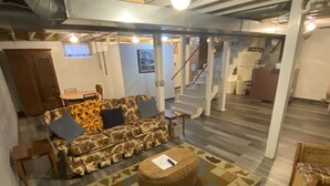 A spacious living area with a sofa set, a coffee table, and a patterned rug. A staircase leads to an upper level.