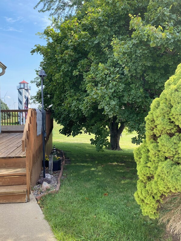 A wooden deck, a large tree, and a lighthouse in the background.