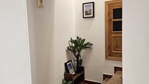 A hallway with a wooden door, a framed picture on the wall, a potted plant, and a staircase. - Visita LA Villa Medieval DE Allariz ! Alojate EN Casa Lina (Allariz)