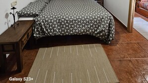 A bedroom with a bed, a wooden ceiling, a door, and a small table. - Visita LA Villa Medieval DE Allariz ! Alojate EN Casa Lina (Allariz)