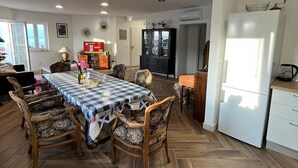 A spacious kitchen with a dining area, featuring a large table with chairs, a refrigerator, and a microwave. - New modern 3-bedroom apartment with AC in Supetar (Selca)