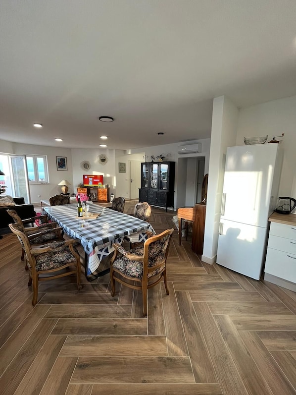 A spacious kitchen with a dining area, featuring a large table with chairs, a refrigerator, and a microwave.