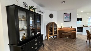 A spacious living room with a herringbone wood floor, a black glass-fronted cabinet, and a wooden dining table with chairs. - New modern 3-bedroom apartment with AC in Supetar (Selca)