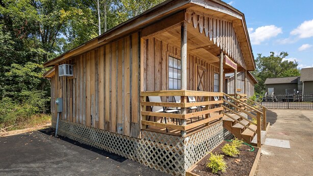 A wooden cabin with a porch and a small staircase leading to a deck area. - Cottage 2 - Bourbon Way (Ridgeland)