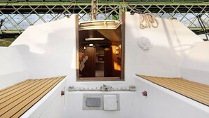 L'intérieur d'un bateau, avec un pont en bois, une petite fenêtre et un mur blanc orné d'un motif représentant un crâne.