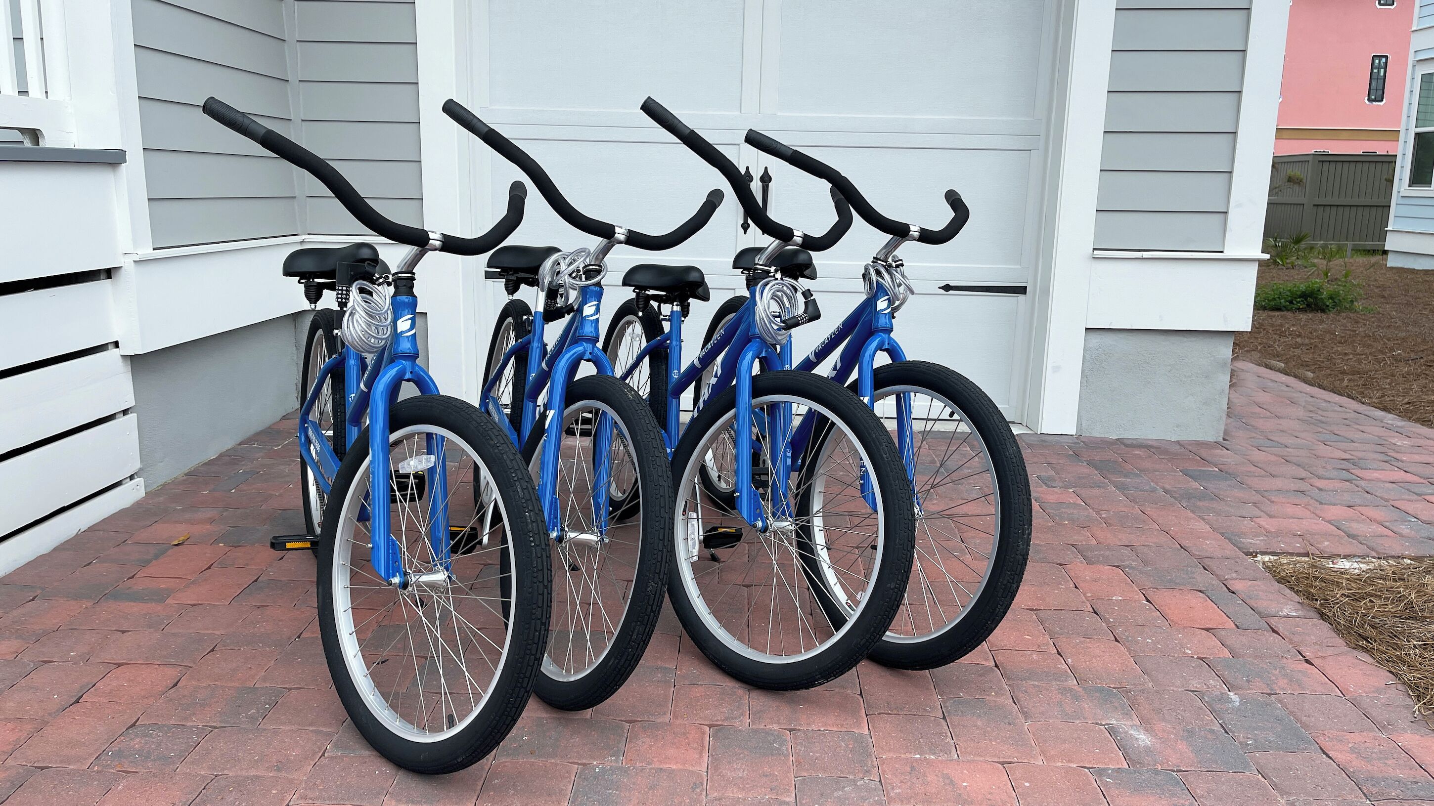 A row of blue bicycles parked in front of a white building with a garage.