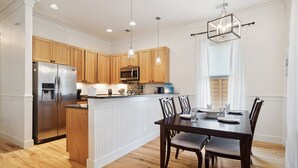 Eine moderne Küche mit Holzausbau, Edelstahlgeräten und einem Essbereich mit dunklem Holztisch und Stühlen.