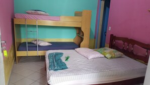 Habitación con literas, un cabecero de madera, una cama individual con colcha a rayas y una pared rosa.