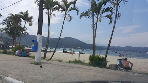 Una playa con palmeras, un camino de arena y barcos en el agua.