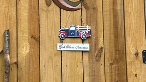 Une clôture en bois sur laquelle est accrochée une pancarte indiquant « TOILETTES » et un croissant de lune décoratif en métal, orné d’étoiles.
